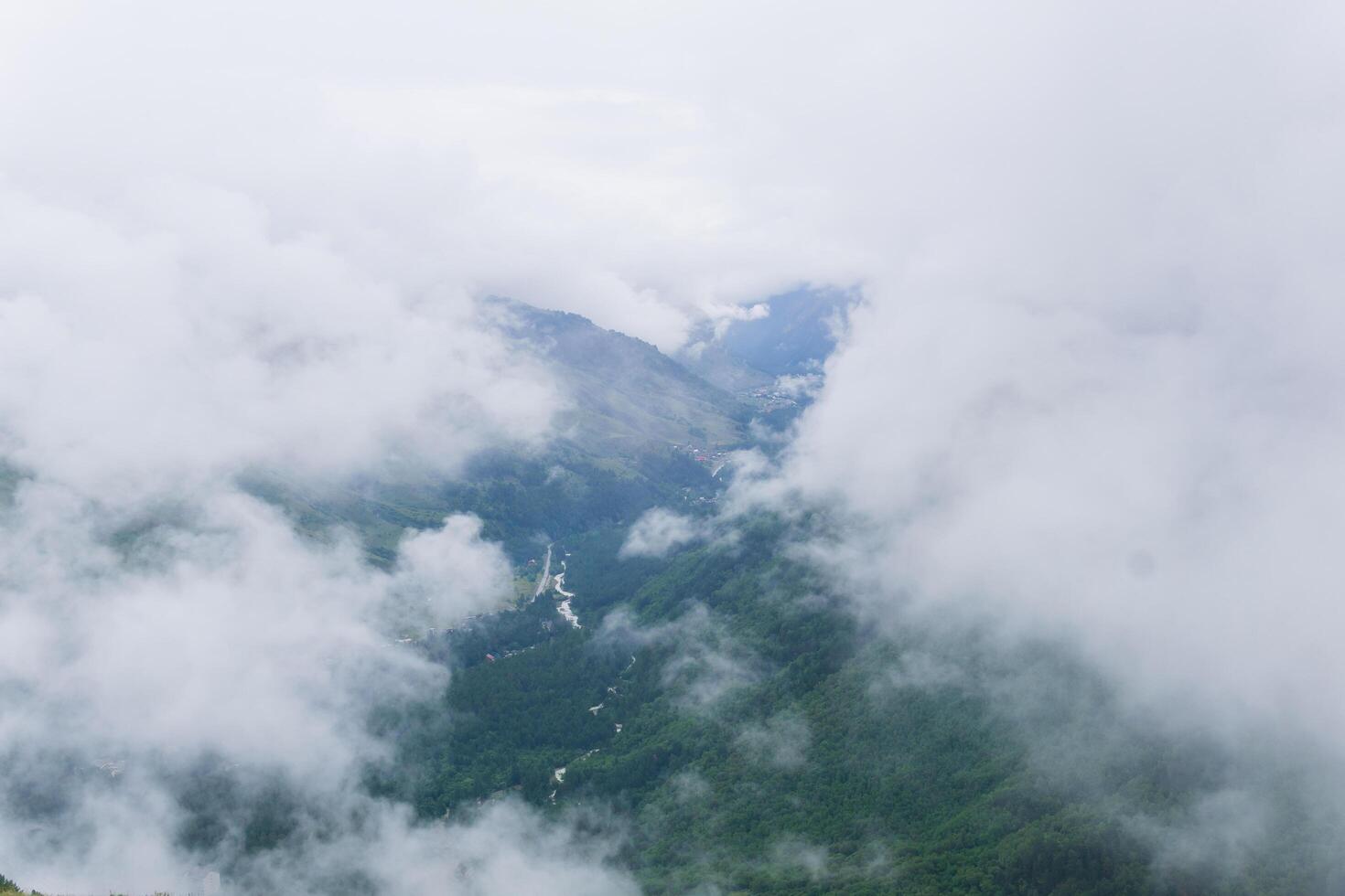 aerial view of wild forested mountain slope through clouds photo