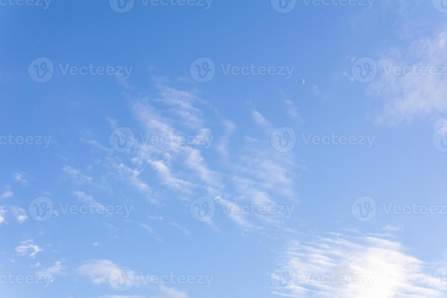 blue sky background with sparse cirrus clouds and moon photo