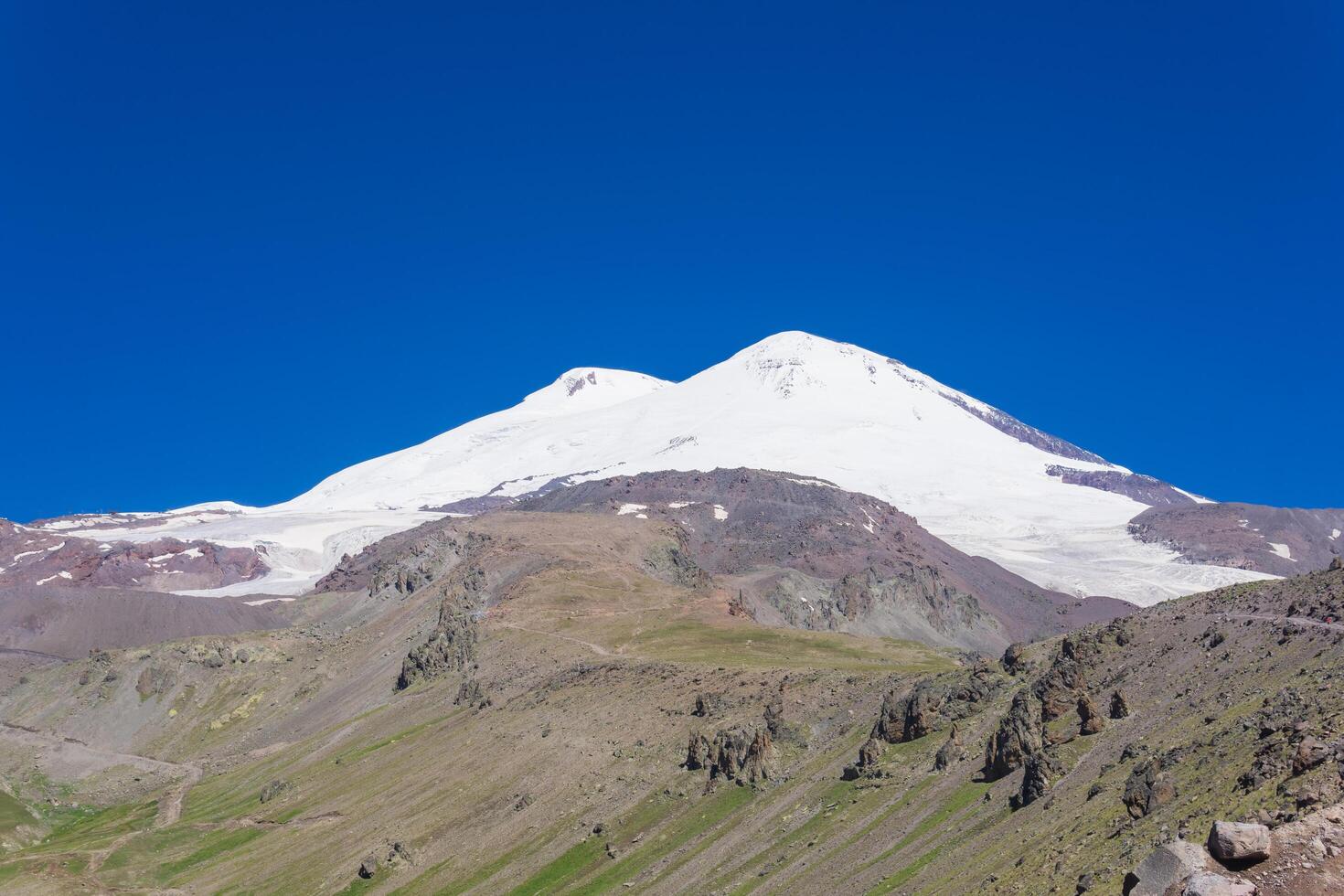 view of the double top of Mount Elbrus and the glacier flowing down from them into the valley photo