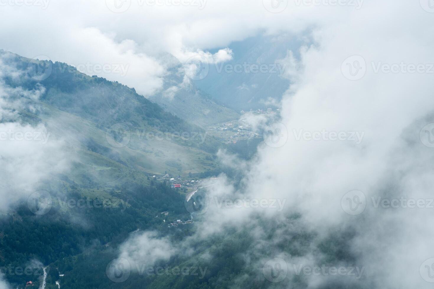aerial view through the clouds to valley with mountain villages photo
