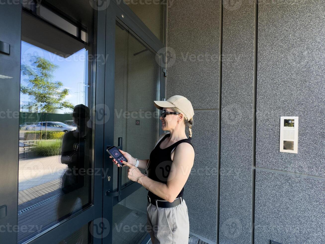 Close up of woman using intercom at building entrance. photo