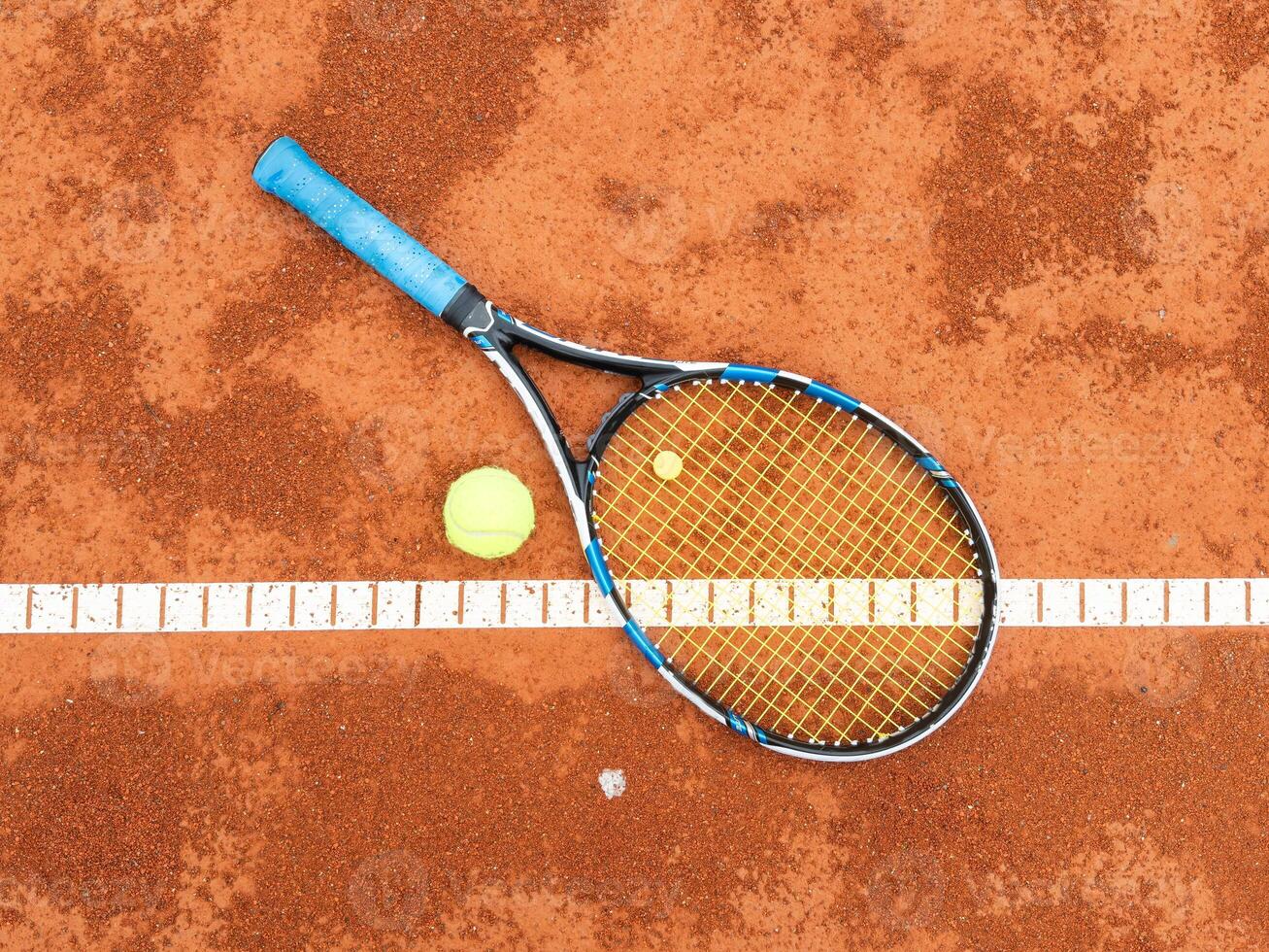 Close up view of tennis racket and ball on the clay tennis court photo