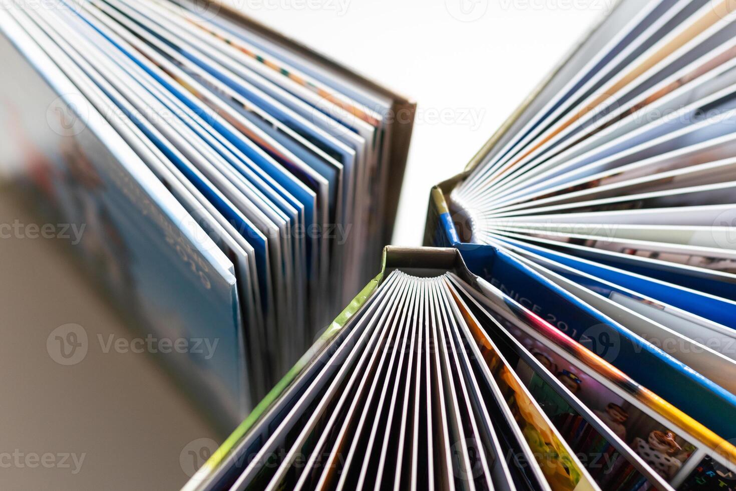on a wooden table and a beige wall there are unfolded and closed white books photo