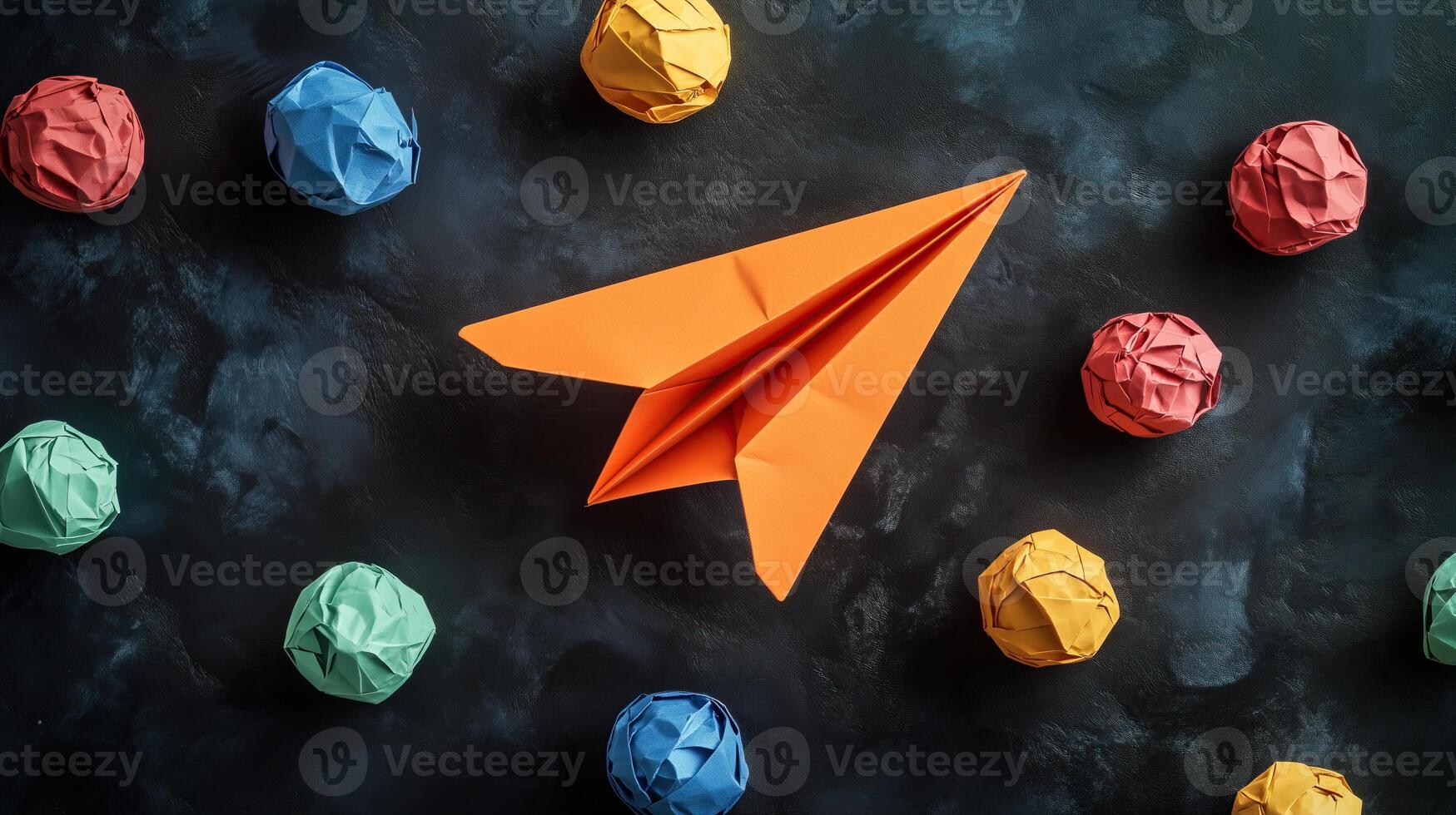 An orange paper airplane surrounded by colorful crumpled paper photo