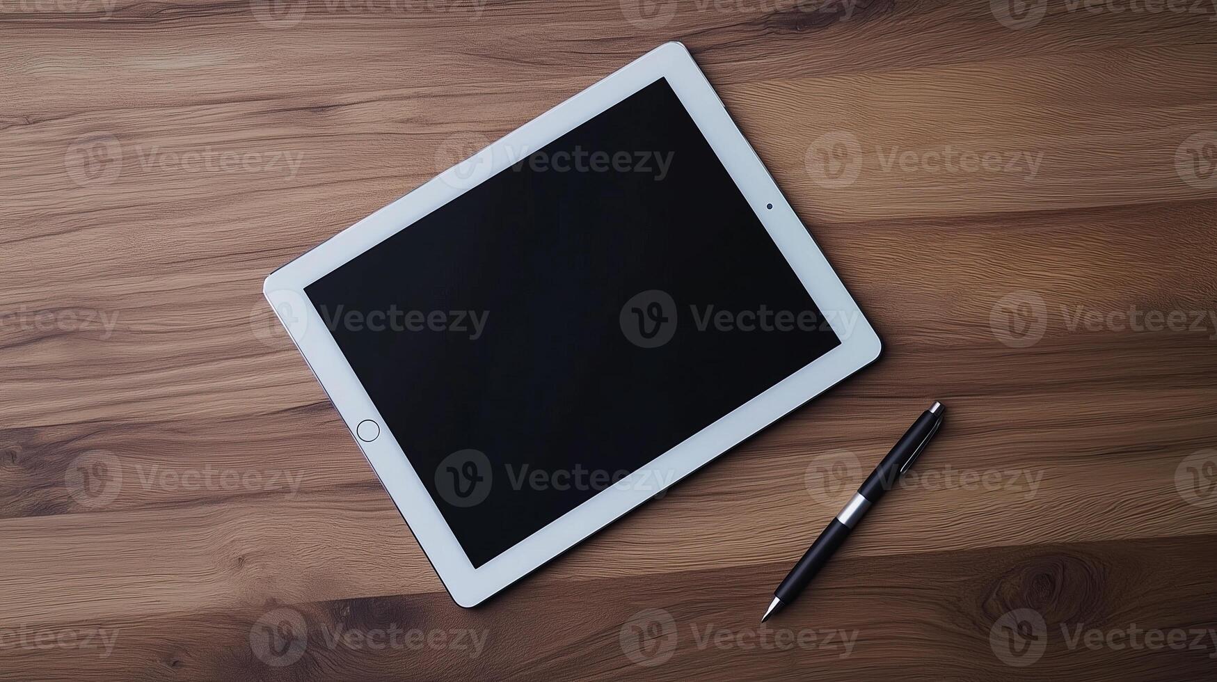 A sleek tablet rests on a wooden surface beside a stylish pen photo