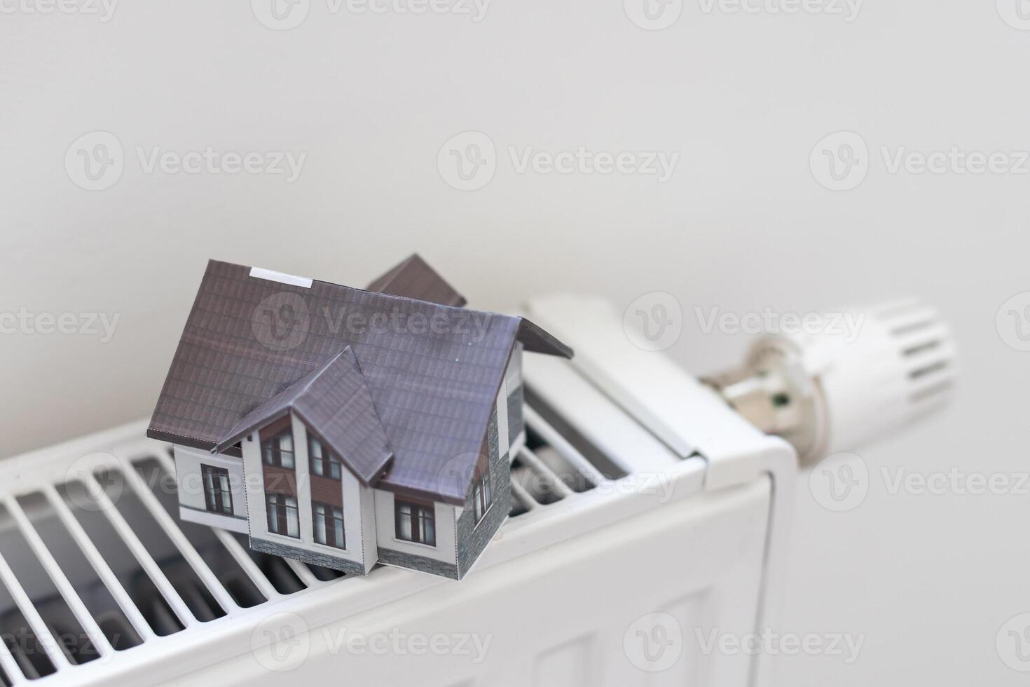 Close-up Of Heating Radiator With Model House In Front Of Blue Wall photo