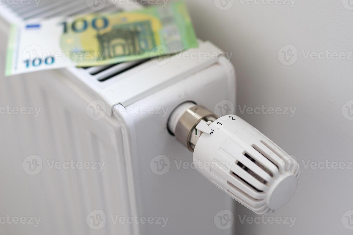 Rising cost of heating and electricity in Europe. Heating radiator with thermostat on which euros lie. Rising energy prices. Energy crisis and recession. 2 euro coins and 100 euro banknotes photo