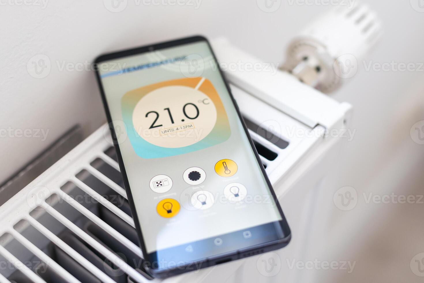 Controlling radiator heating temperature with a smart phone, close-up with radiator on the background. Concept of a smart home and mobile application for managing smart devices at home photo