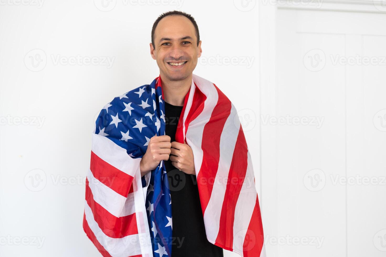 Celebrating an Independence day. Stars and Stripes. Young man with the flag of the United States of America isolated on white studio background. Looks crazy happy and proud as a patriot of his country photo
