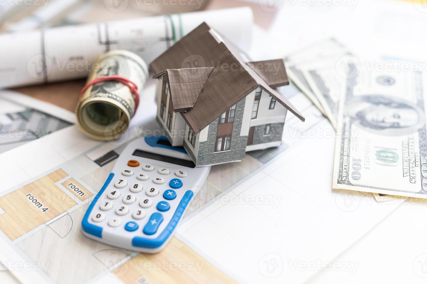 white metal model house with calculator and plans of building on white table with euro banknotes. costs of building a house. taking a loan photo