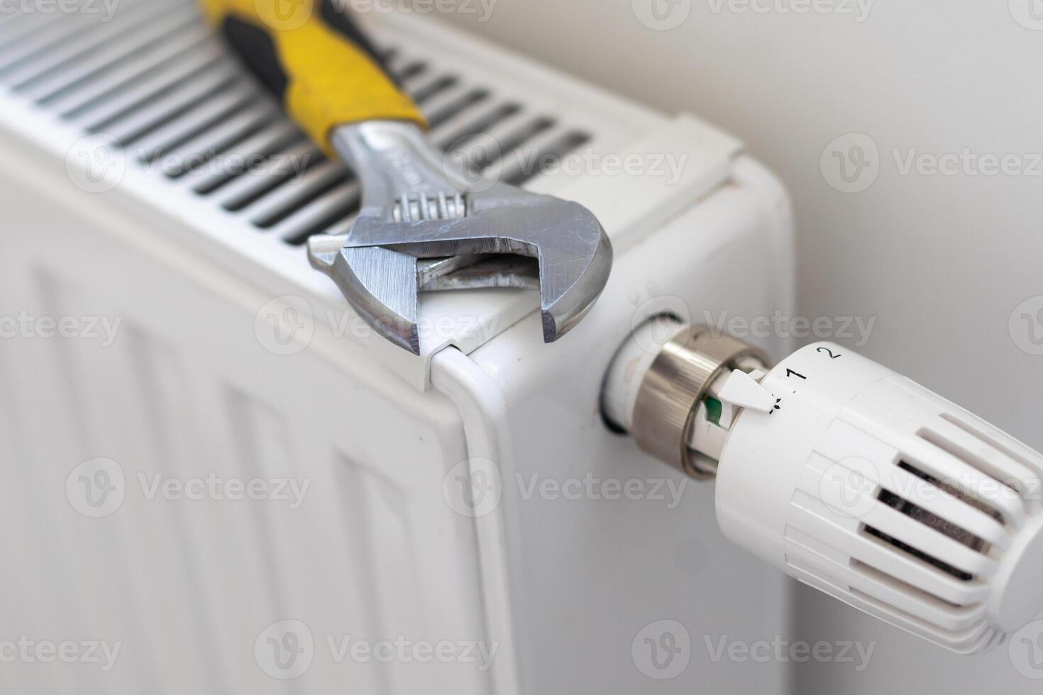 New thermostat, adjustable wrench and PTFE tape on the heating radiator. Installation of a thermostat for better energy efficiency, gas savings in home heating. Plumbing work and service. photo