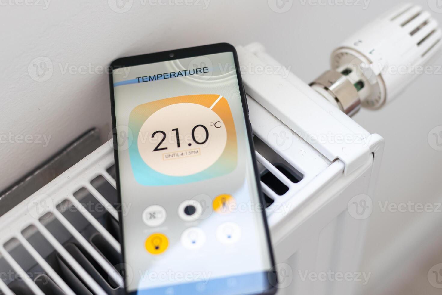 Adjusting Temperature Of Digital Smart Thermostat Using Mobile Phone App At Home photo