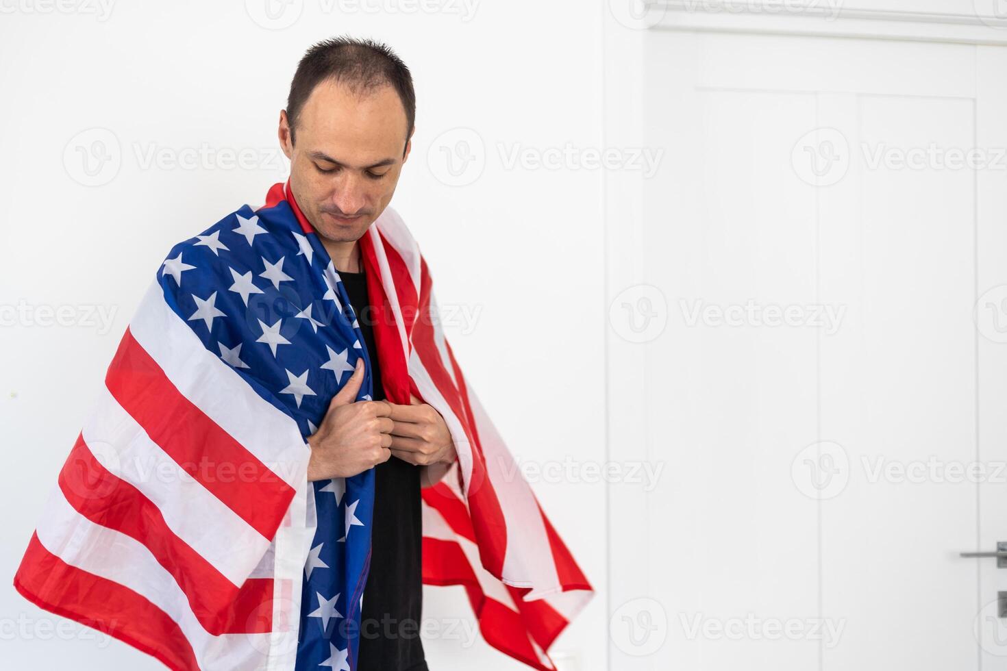 Beautiful young man holding an American flag on grey background photo