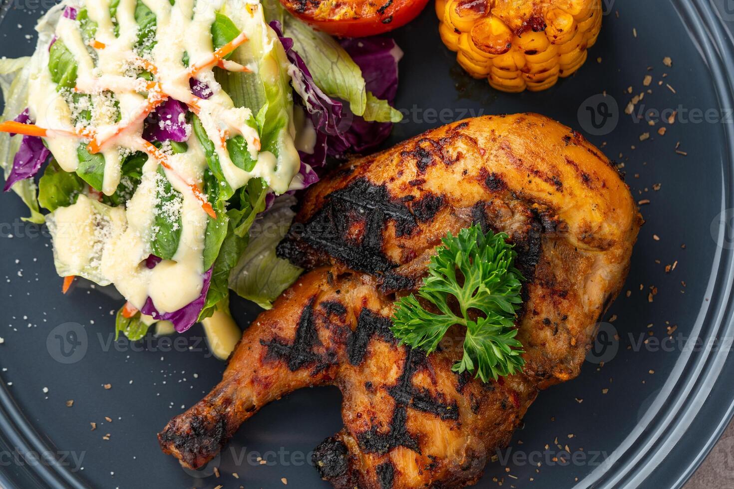 Half chicken baked in a sauce of garlic, soy, ginger, and honey. plate with baked corn, salad and tomatoes. photo
