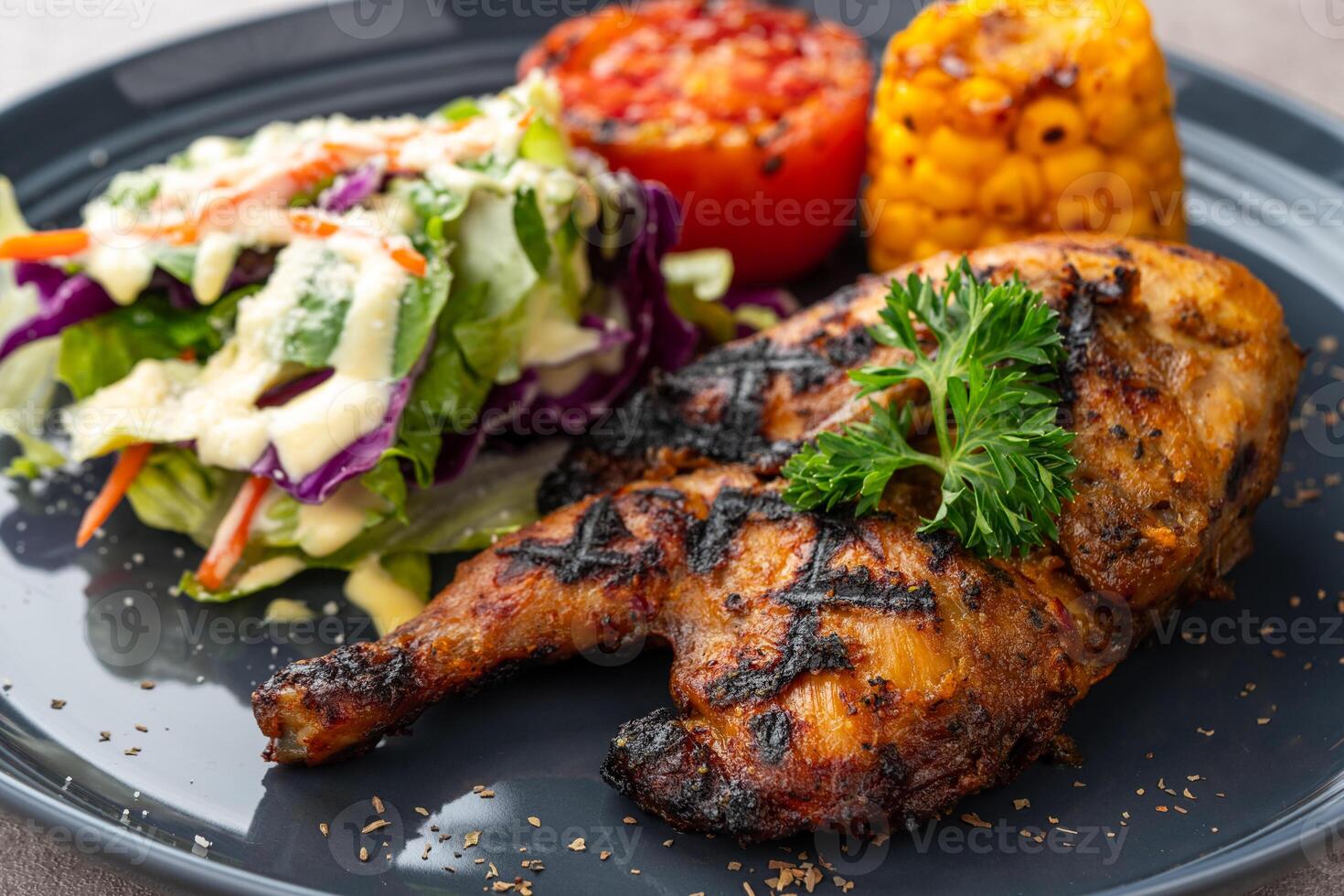 Half chicken baked in a sauce of garlic, soy, ginger, and honey. plate with baked corn, salad and tomatoes. photo