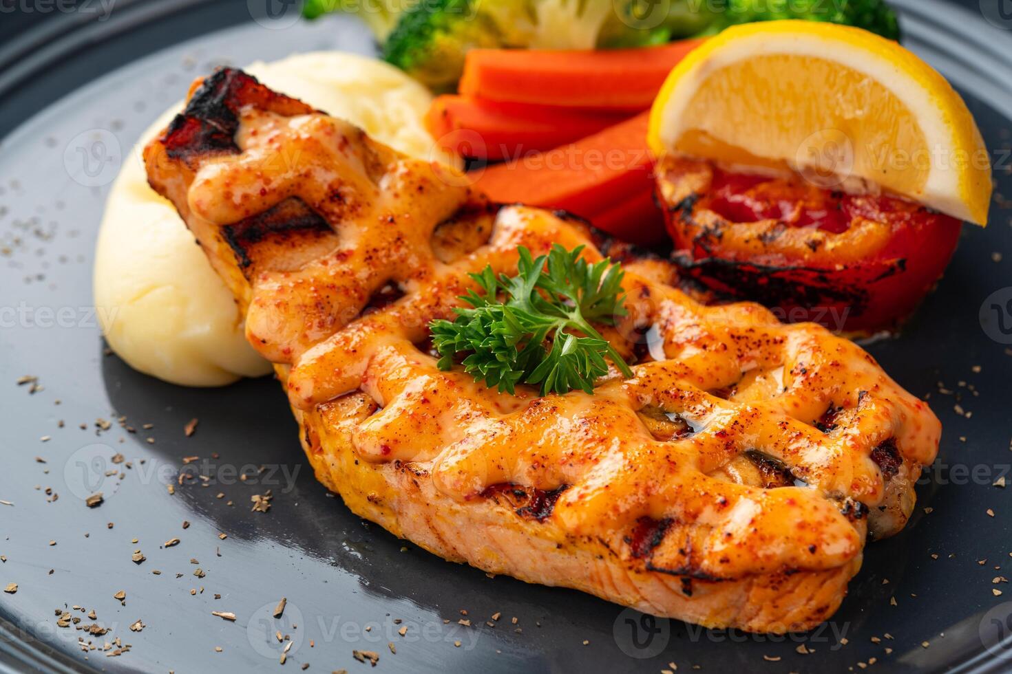 Grilled salmon fillets with mentai sauce and mash potato plating on black plate with negative space for text. photo