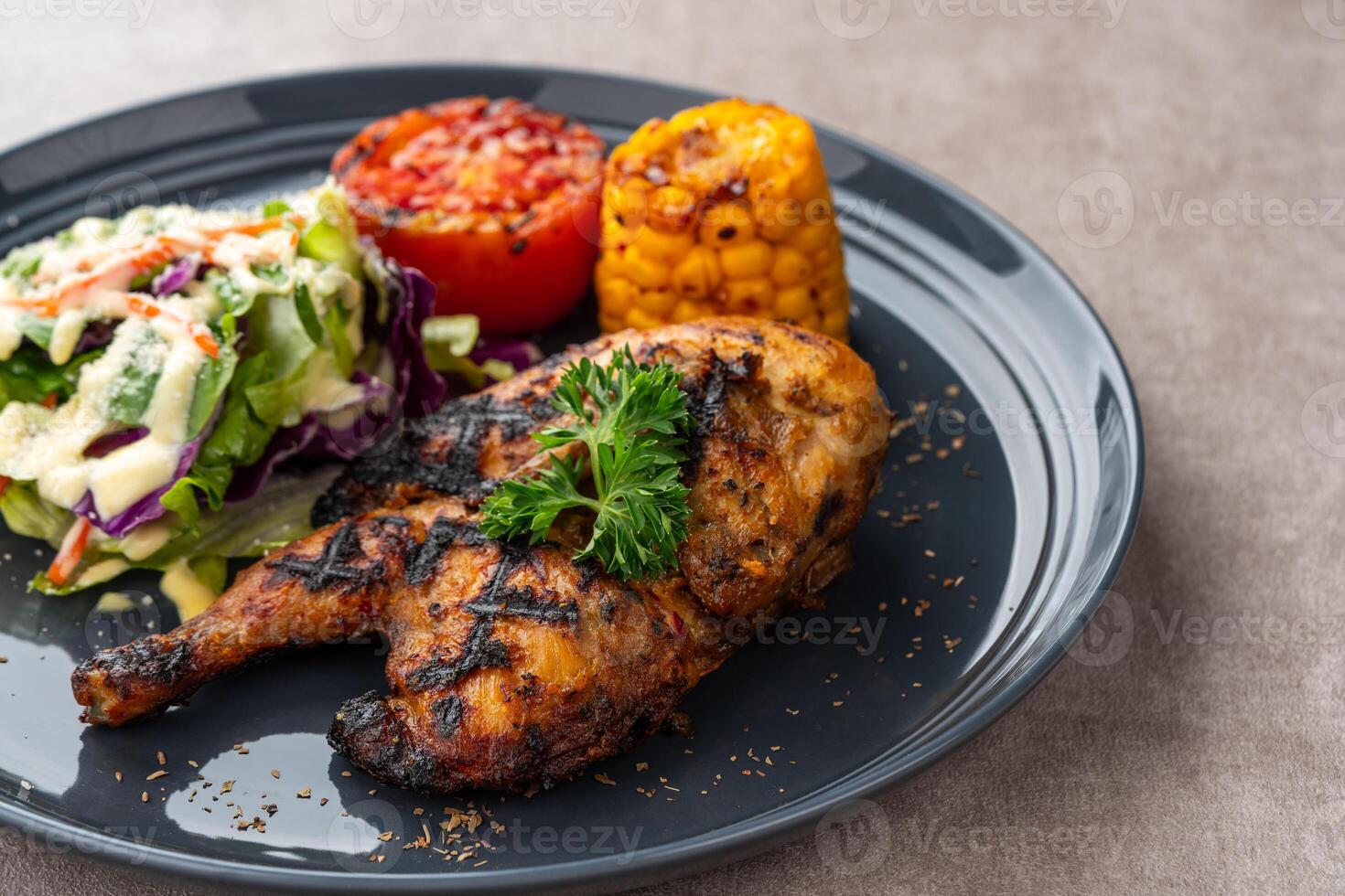 Half chicken baked in a sauce of garlic, soy, ginger, and honey. plate with baked corn, salad and tomatoes. photo