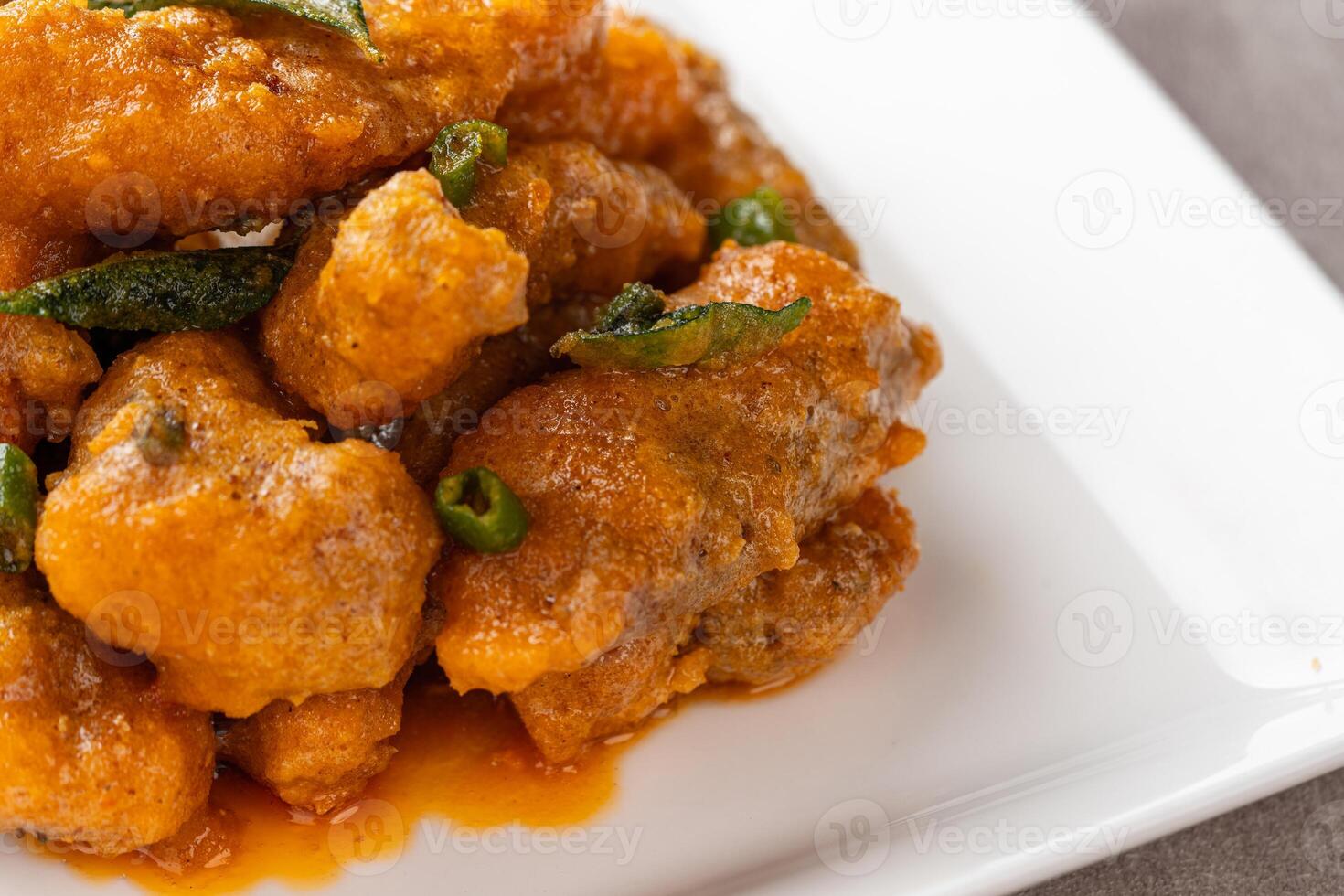 Crispy fried dori fish coated with salted egg plated on a white plate photo
