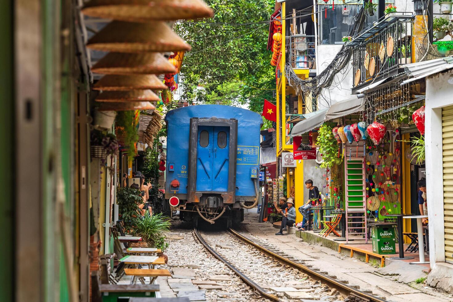 Hanoi, Vietnam - 27 Jun 2024 A train passes through a narrow street in Hanoi's Old Quarter. Tourists take photos of the speeding train. Hanoi's Train Street is a popular tourist attraction.