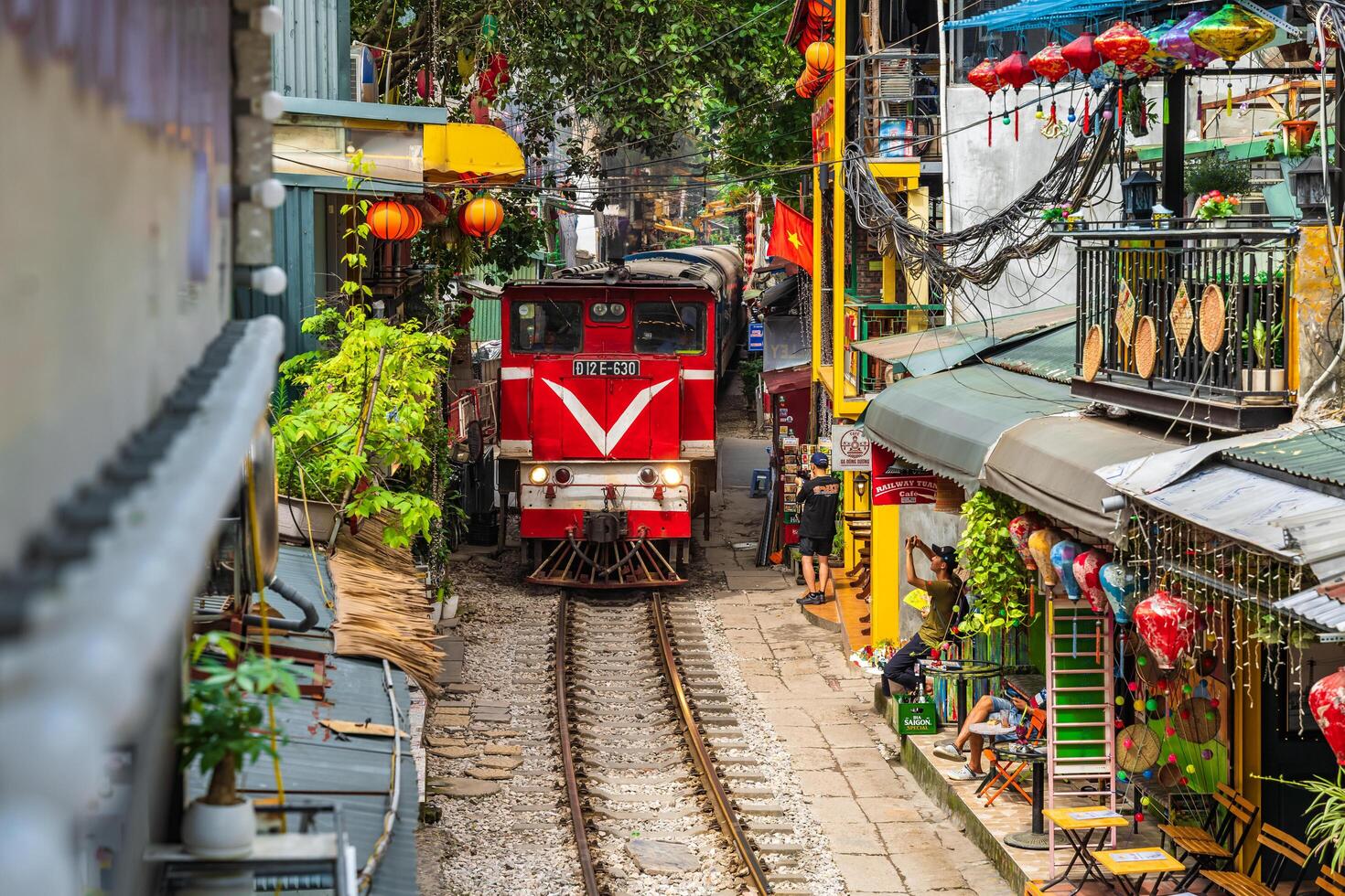 Hanoi, Vietnam - 27 Jun 2024 A train passes through a narrow street in Hanoi's Old Quarter. Tourists take photos of the speeding train. Hanoi's Train Street is a popular tourist attraction.