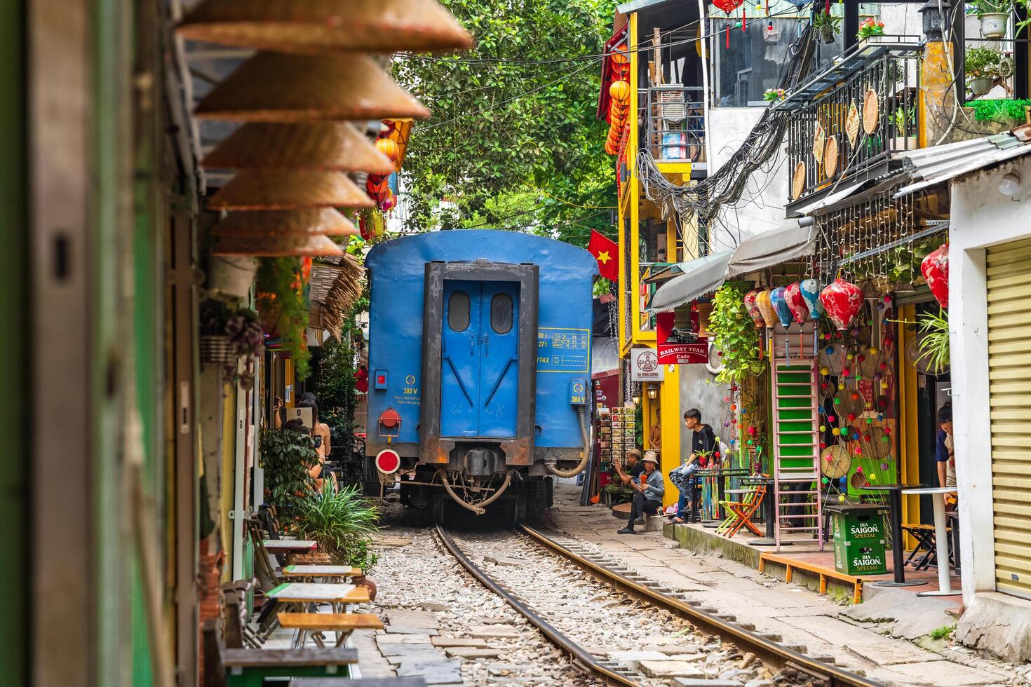 Hanoi, Vietnam - 27 Jun 2024 A train passes through a narrow street in Hanoi's Old Quarter. Tourists take photos of the speeding train. Hanoi's Train Street is a popular tourist attraction.