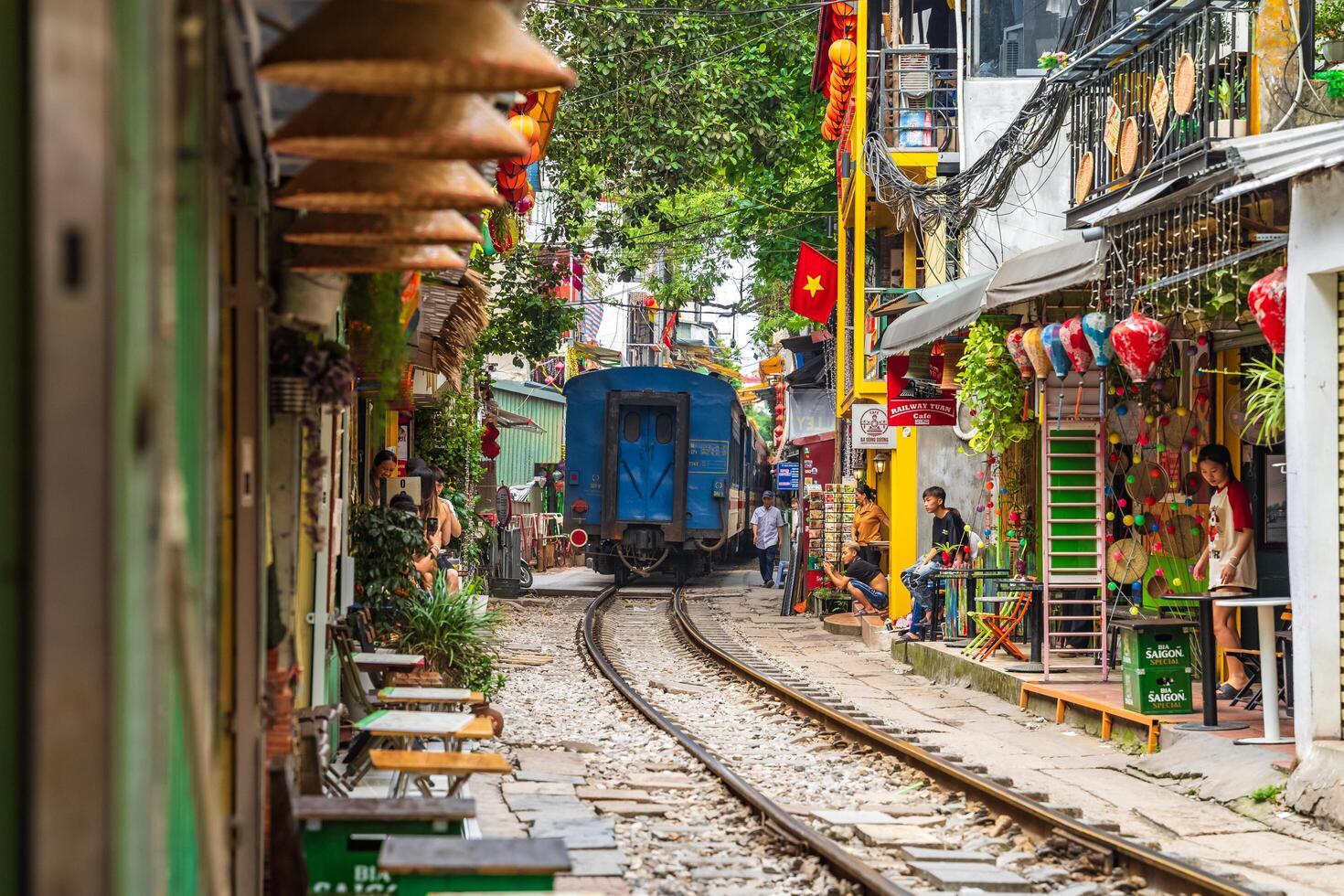 Hanoi, Vietnam - 27 Jun 2024 A train passes through a narrow street in Hanoi's Old Quarter. Tourists take photos of the speeding train. Hanoi's Train Street is a popular tourist attraction.