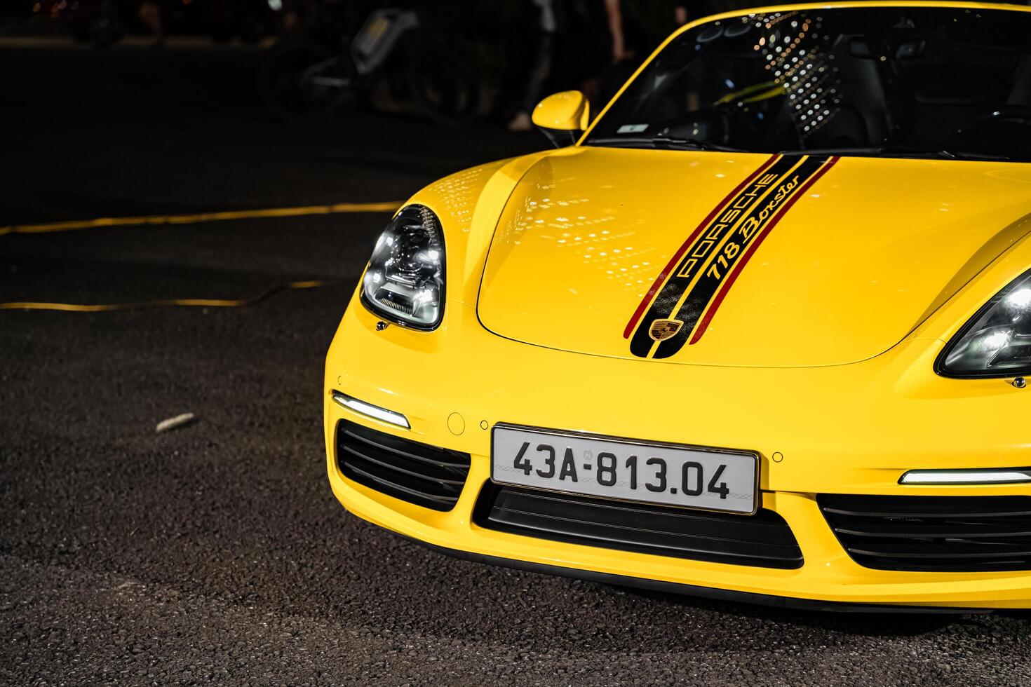 Hanoi, Vietnam - 26 Jun 2024 A yellow Porsche 718 Boxster parked on the street in Hanoi, Vietnam. Porsche is a German automobile manufacturer. photo