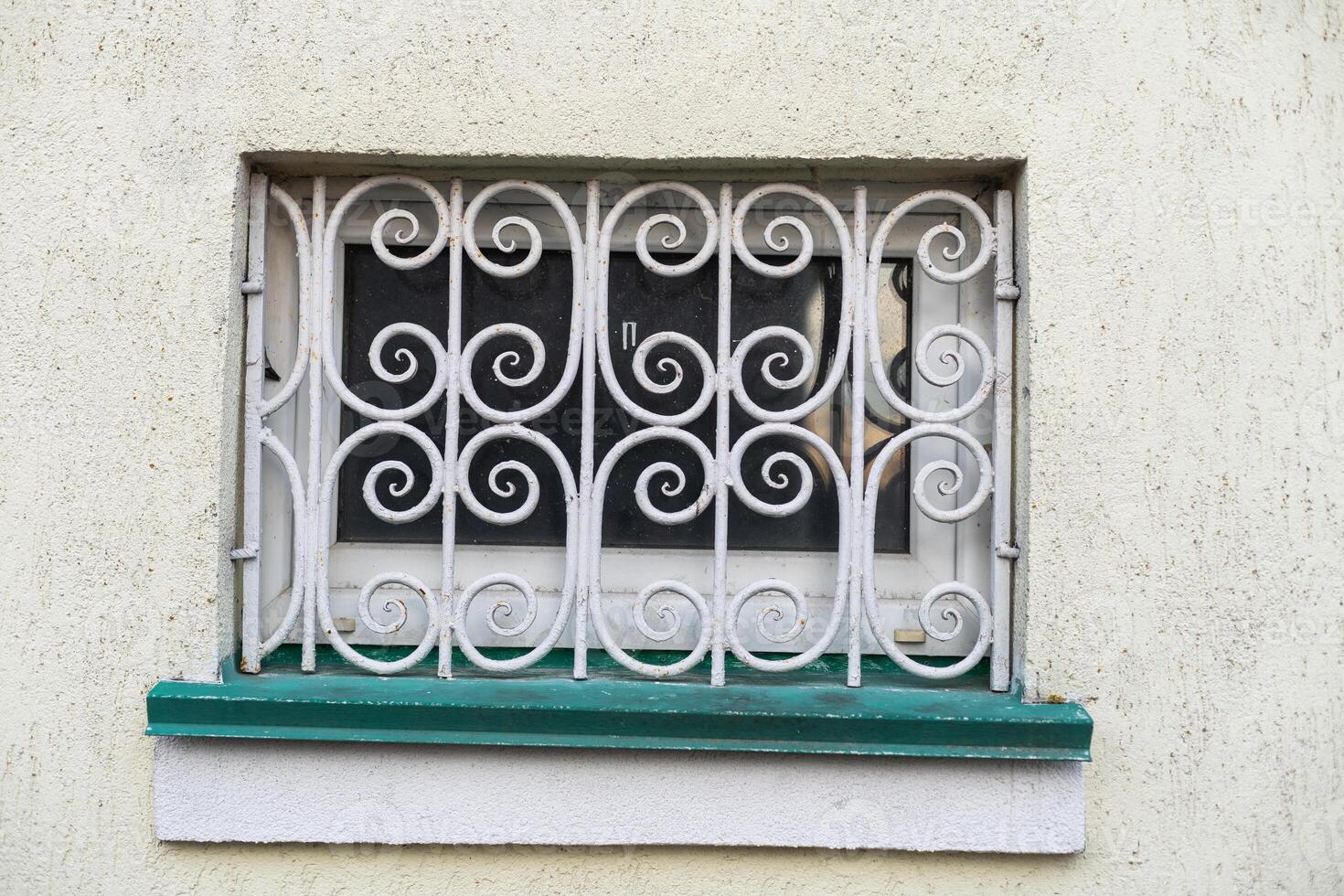 Forged lattice with pattern on closed window of an antique red brick rear. photo