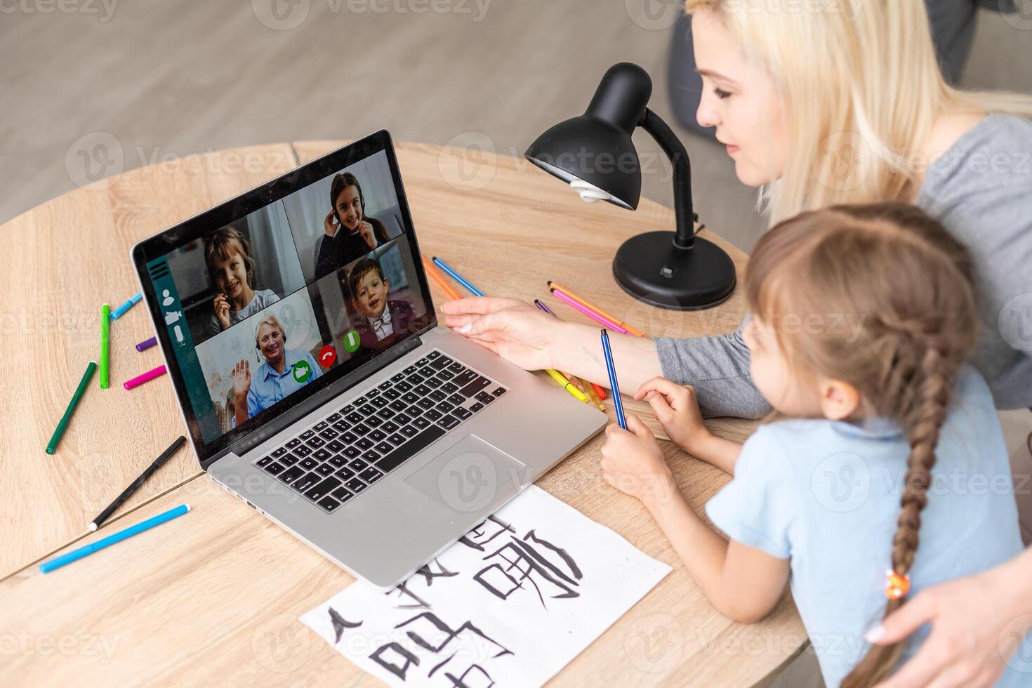 Private lesson. Attentive young woman tutor teacher help little girl pupil with studying math language correct mistakes explain learning material. Smiling mother assist small daughter with home task photo