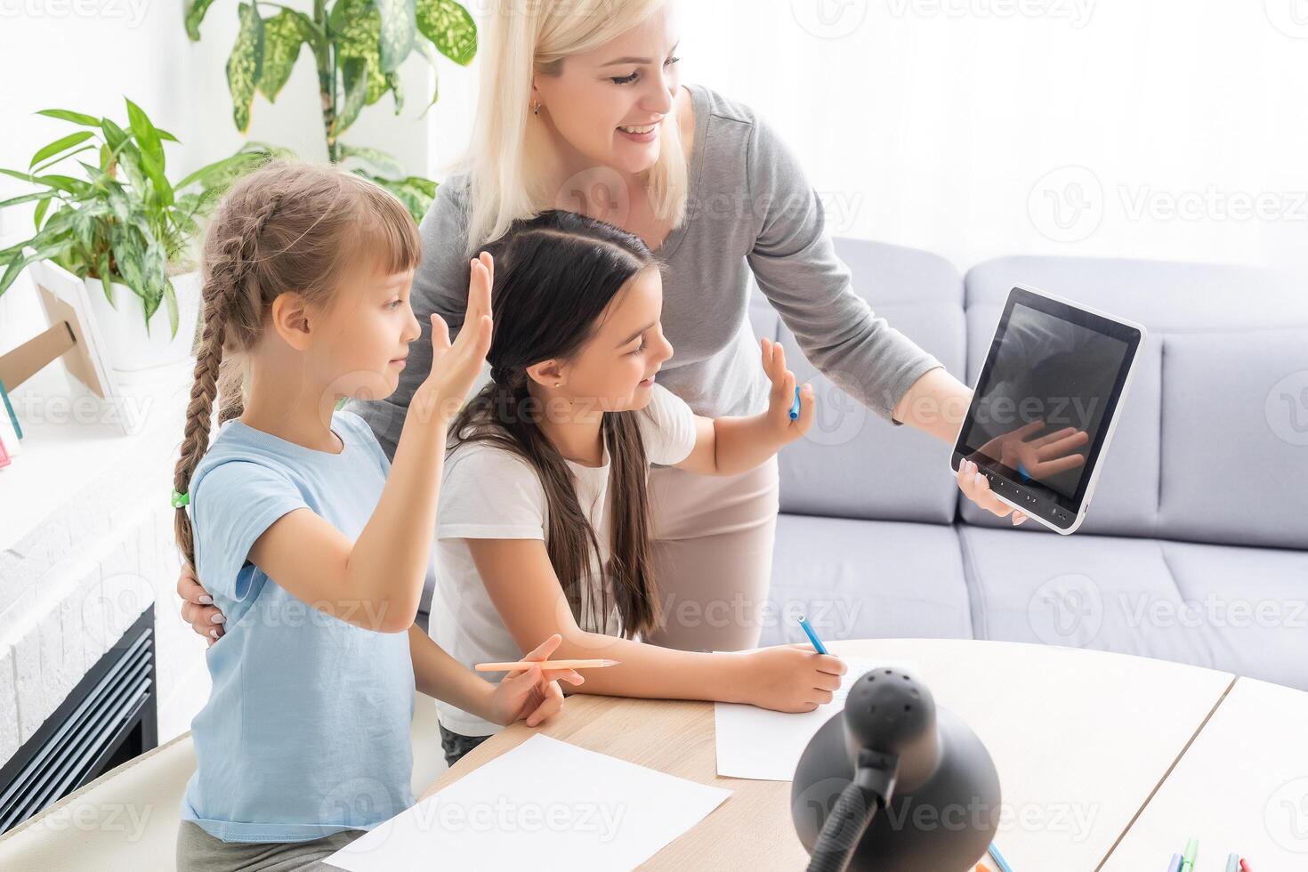 Homeschool young two little daughters learning internet online do homework by using computer with mother help, teach and encourage. Girl and baby sister happy to study education at home together photo