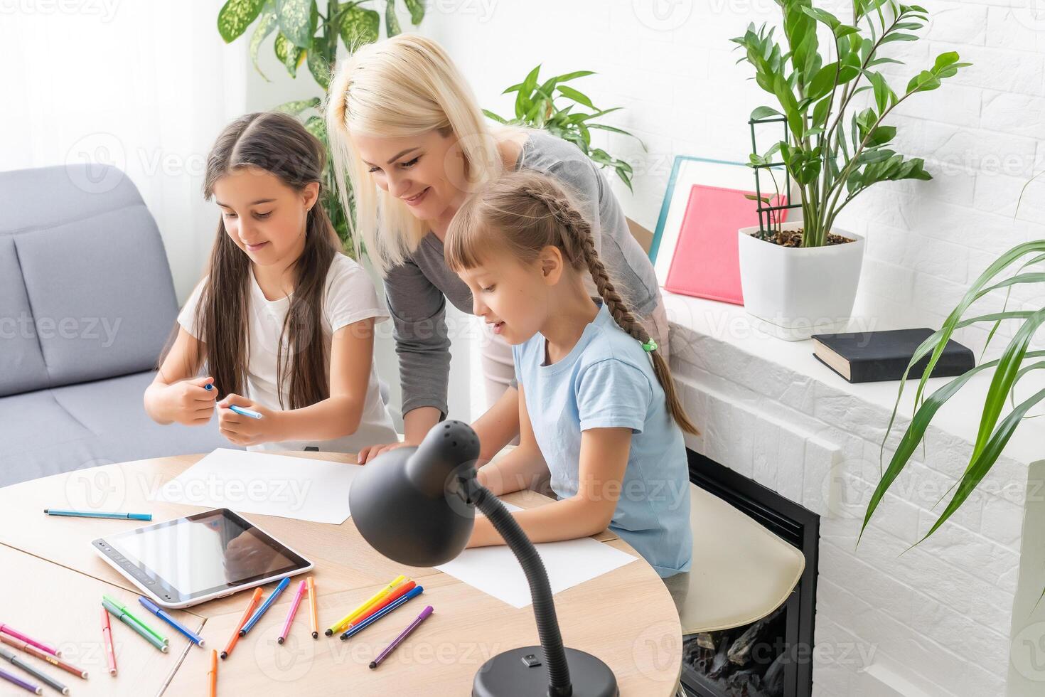 mother and two daughters doing homework writing and reading at home photo
