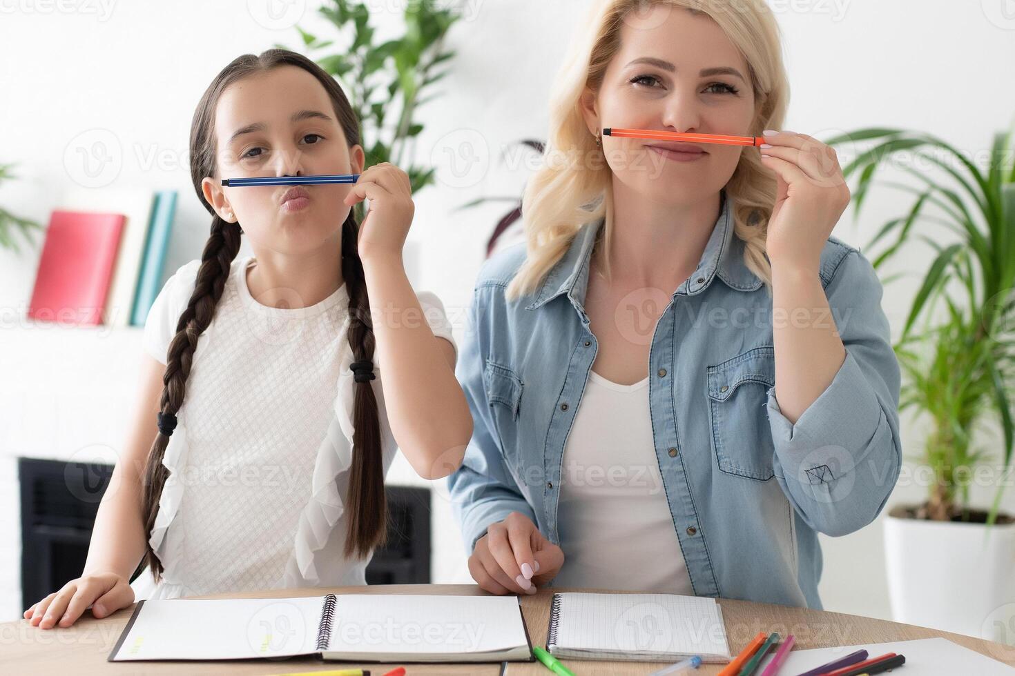 schoolgirl and mother together doing homework in home photo