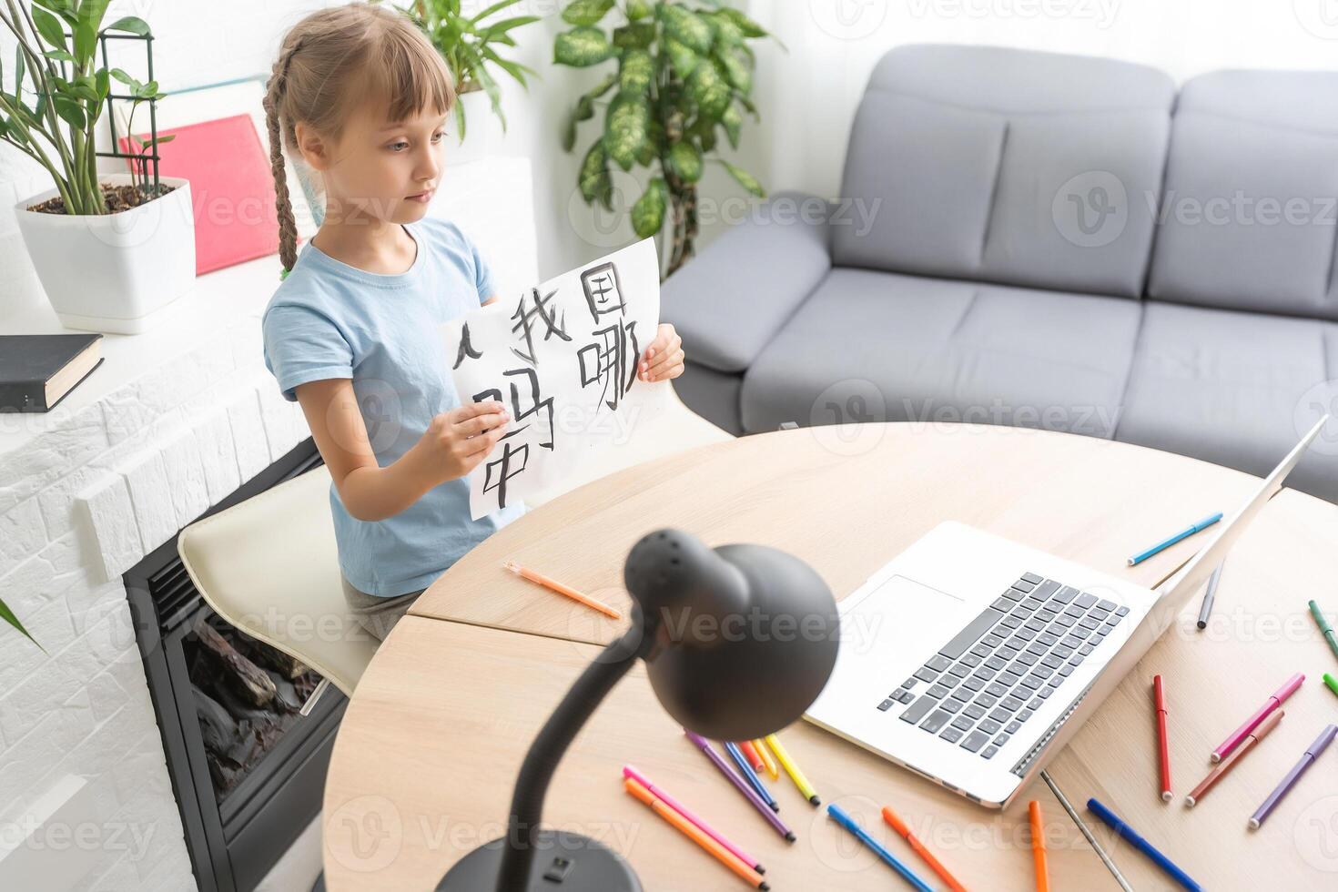 little girl learning chinese while using her laptop computer in the living room at home. family activity concept. photo