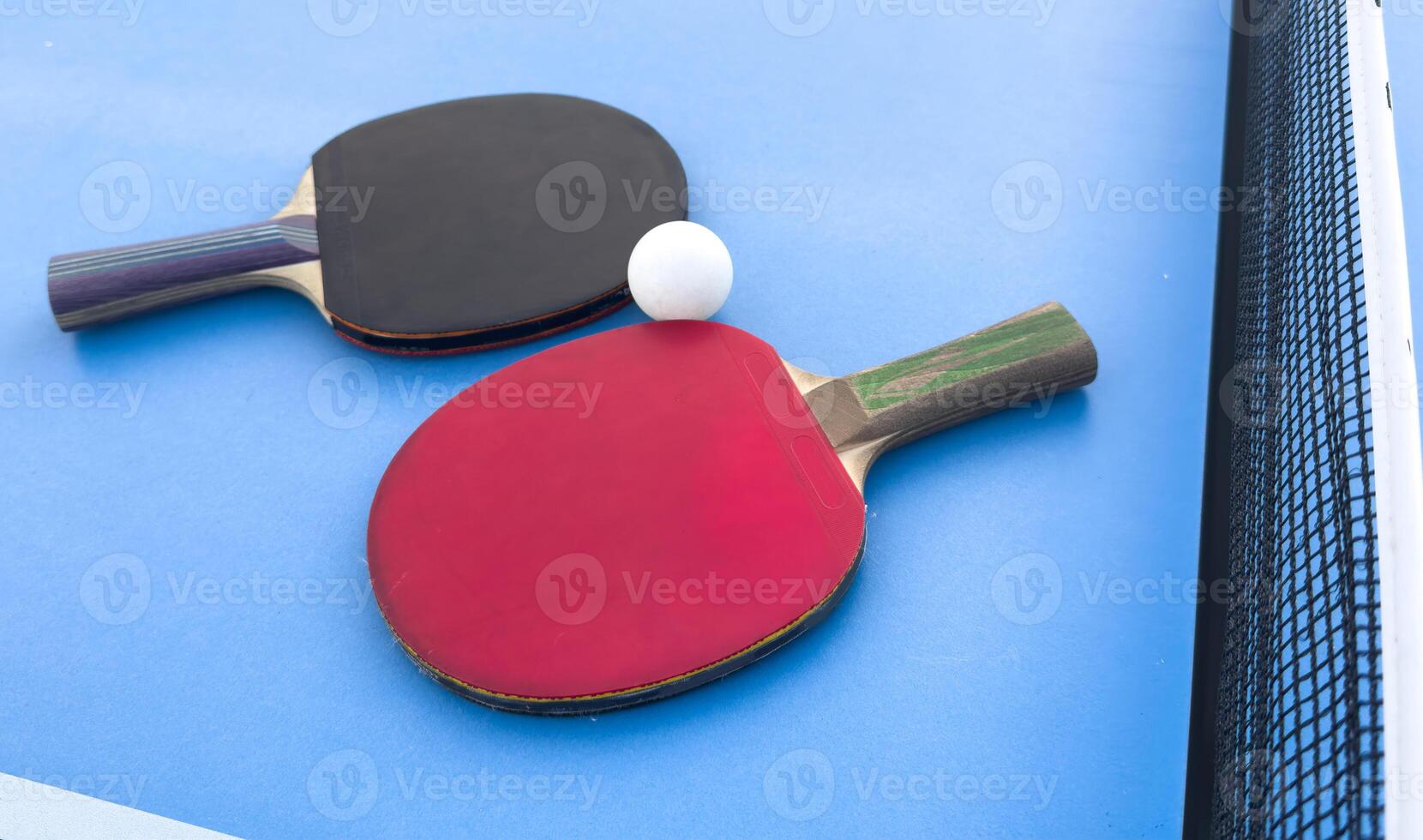 Background with set of table tennis paddles, and white ball isolated on blue table. Top view. photo