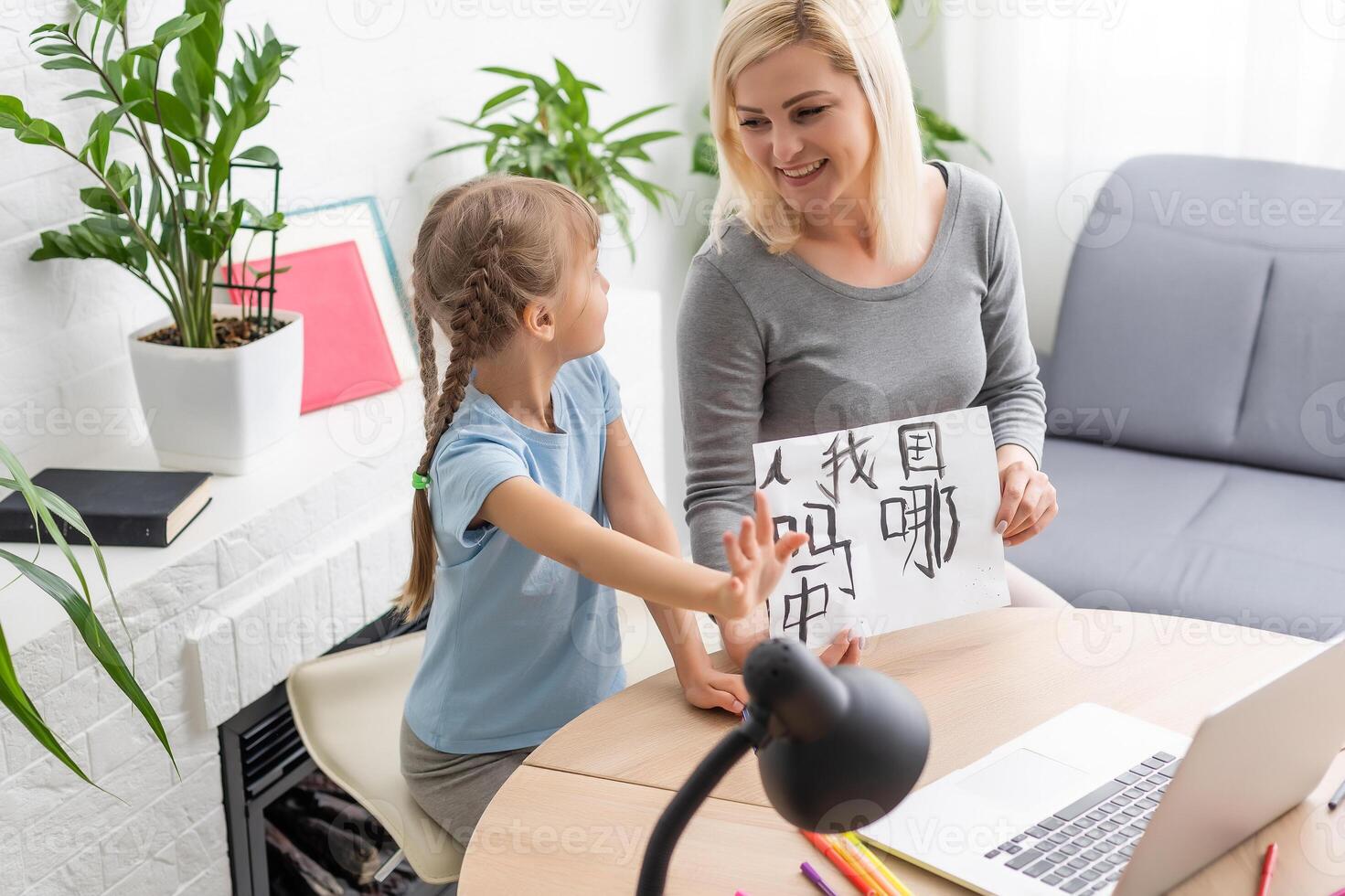 Private lesson. Attentive young woman tutor teacher help little girl pupil with studying math language correct mistakes explain learning material. Smiling mother assist small daughter with home task photo