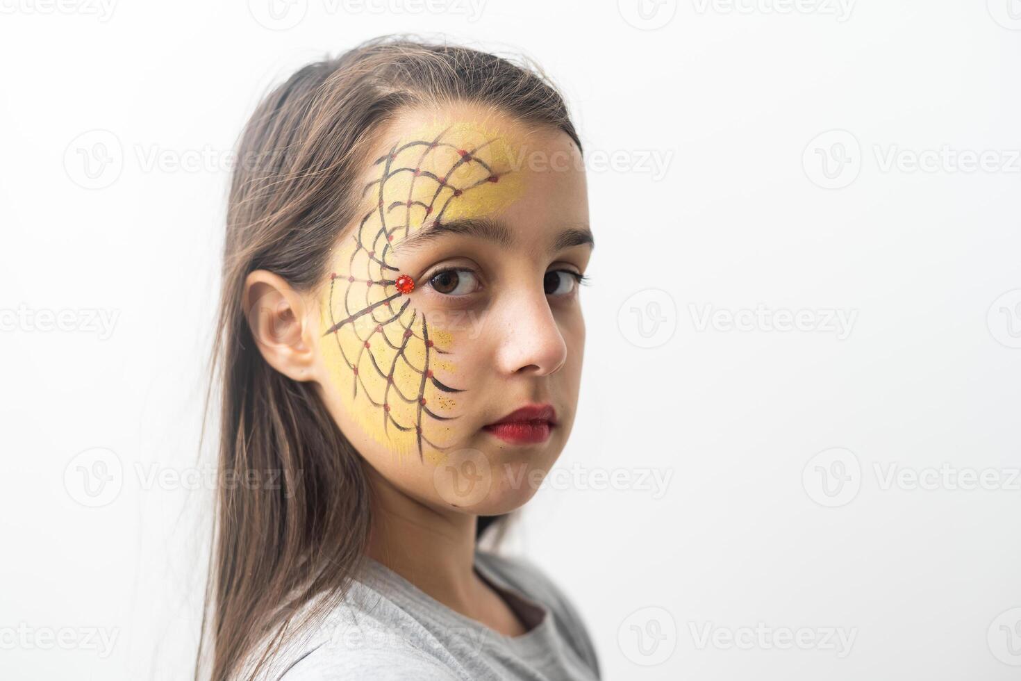 Portrait of a caucasian teenage girl with a cobweb and a spider on her face photo