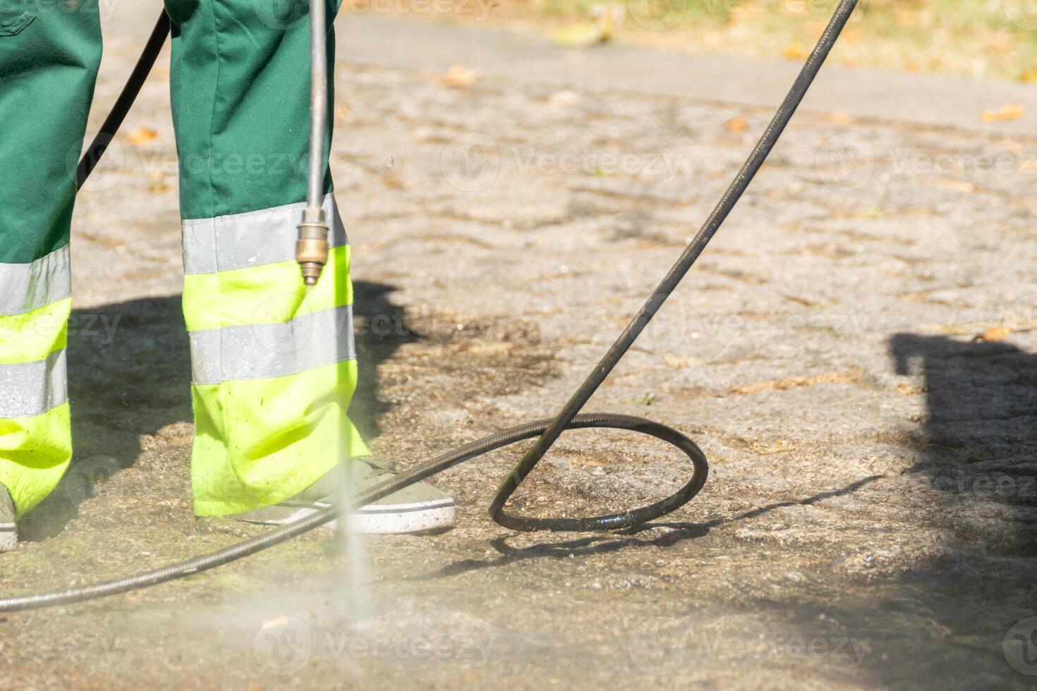 selective focus, a public cleaning worker cleaning the street with high pressurized water photo