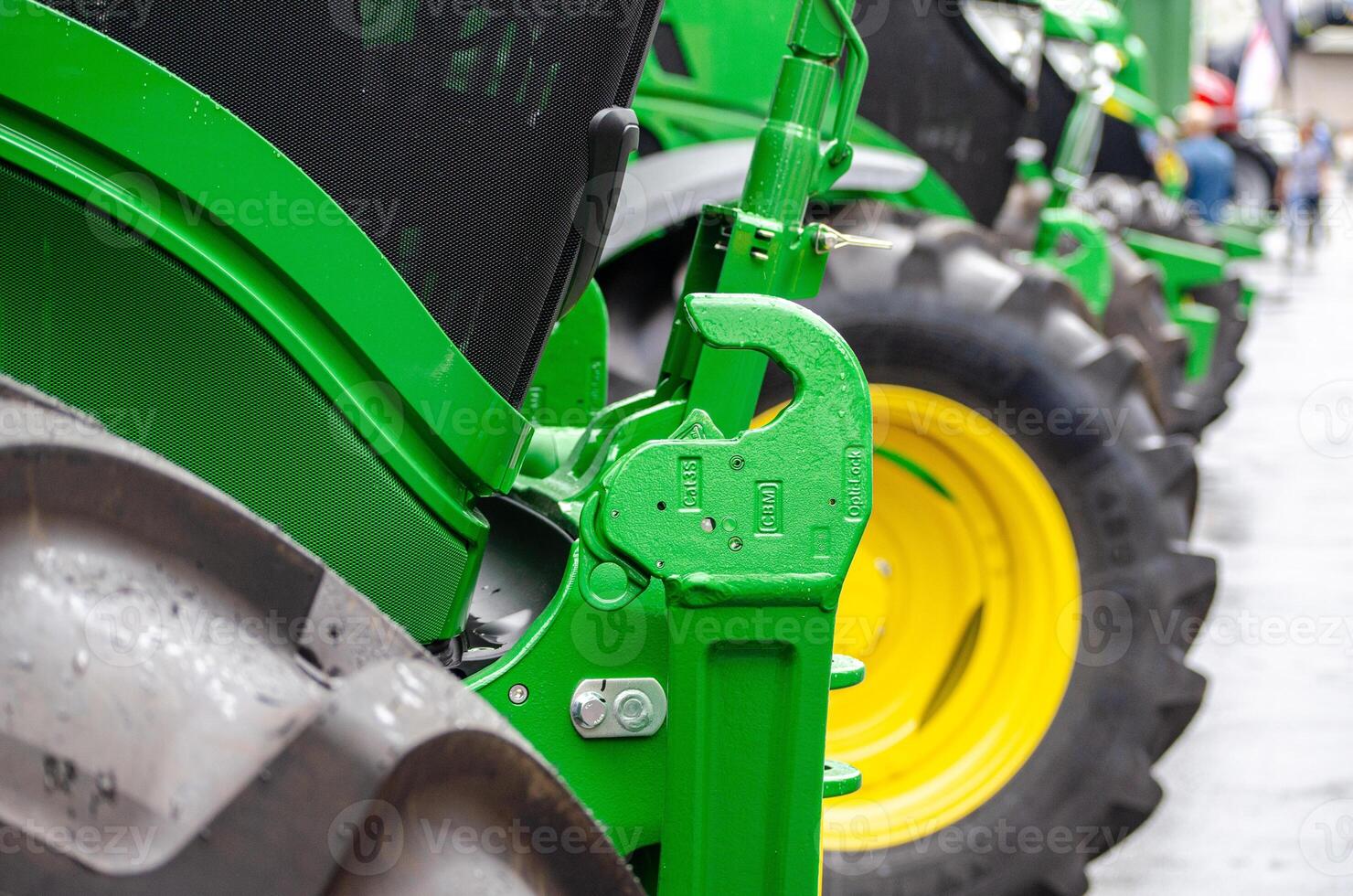 partial view of several green tractors in a row at an exhibition of agricultural machinery for sale photo