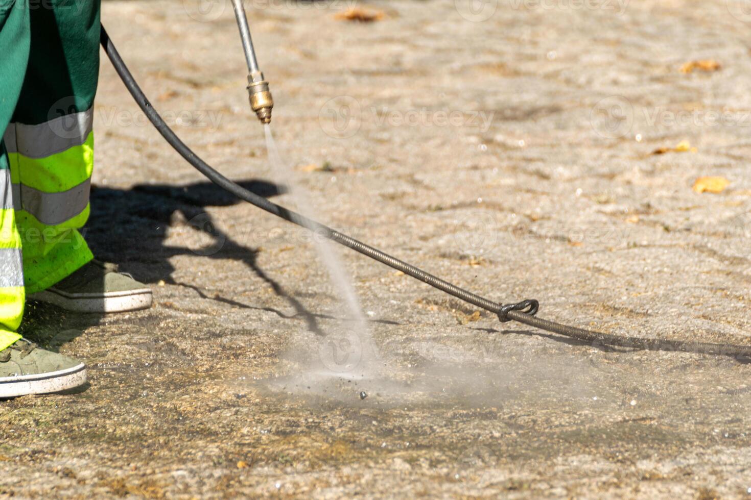 selective focus, a public cleaning worker cleaning the street with pressure water photo
