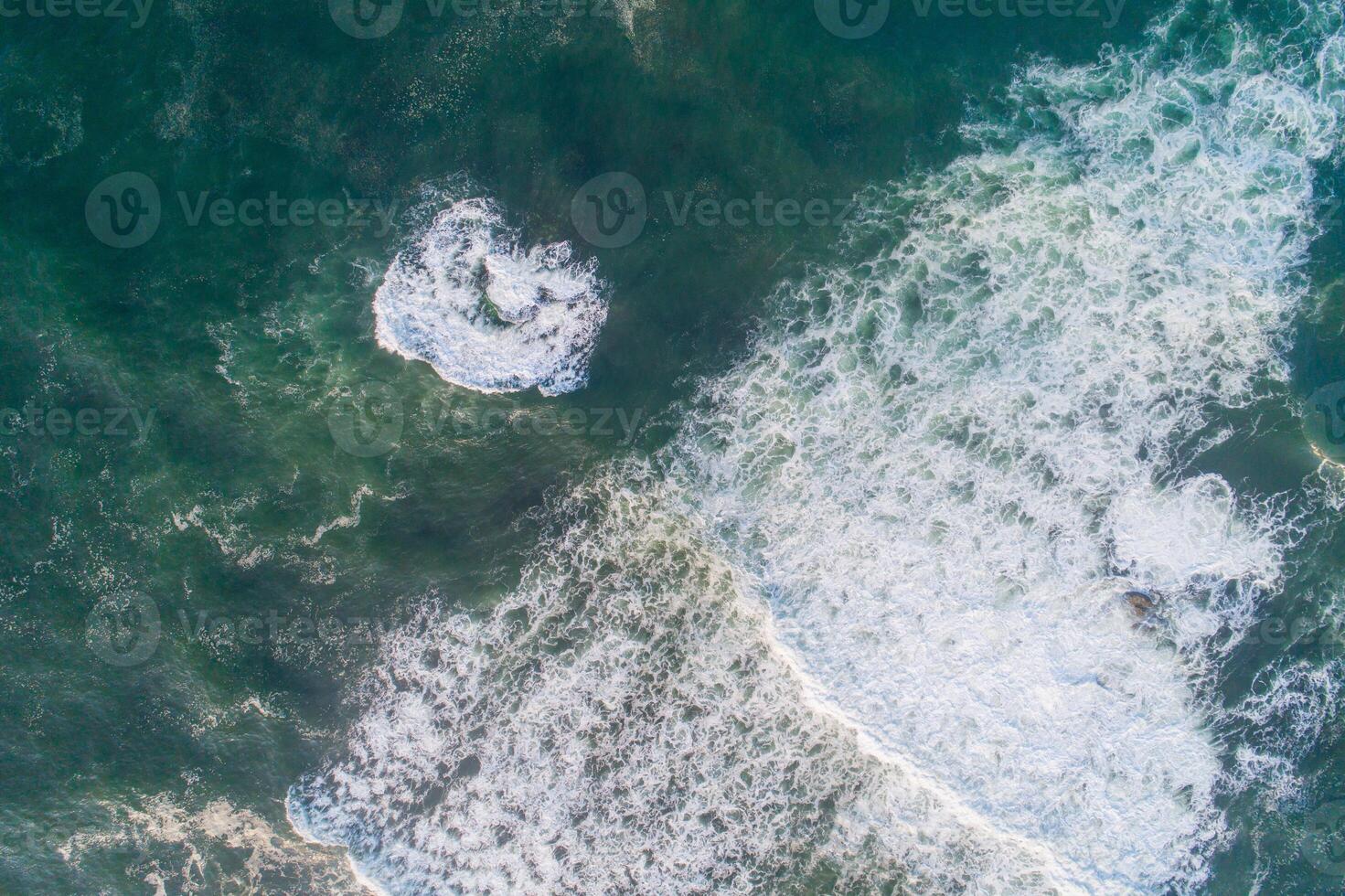 aerial drone view of some ocean waves breaking on a green water sea photo