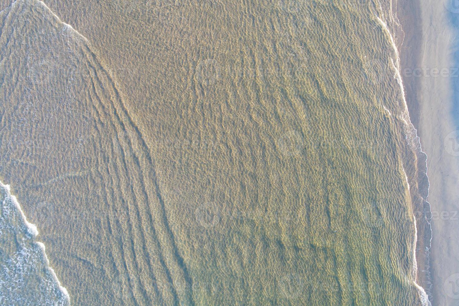 overhead aerial drone view of water on the shore of a beach at sunrise in northern Portugal photo