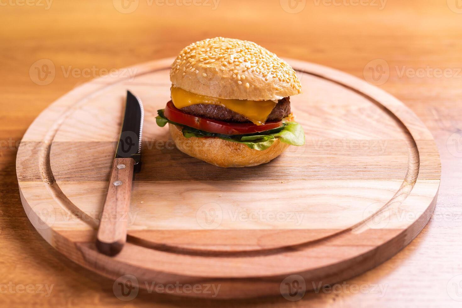Delicious homemade burger of beef and cheese and vegetables on an wooden table. Fat unhealthy food close-up photo