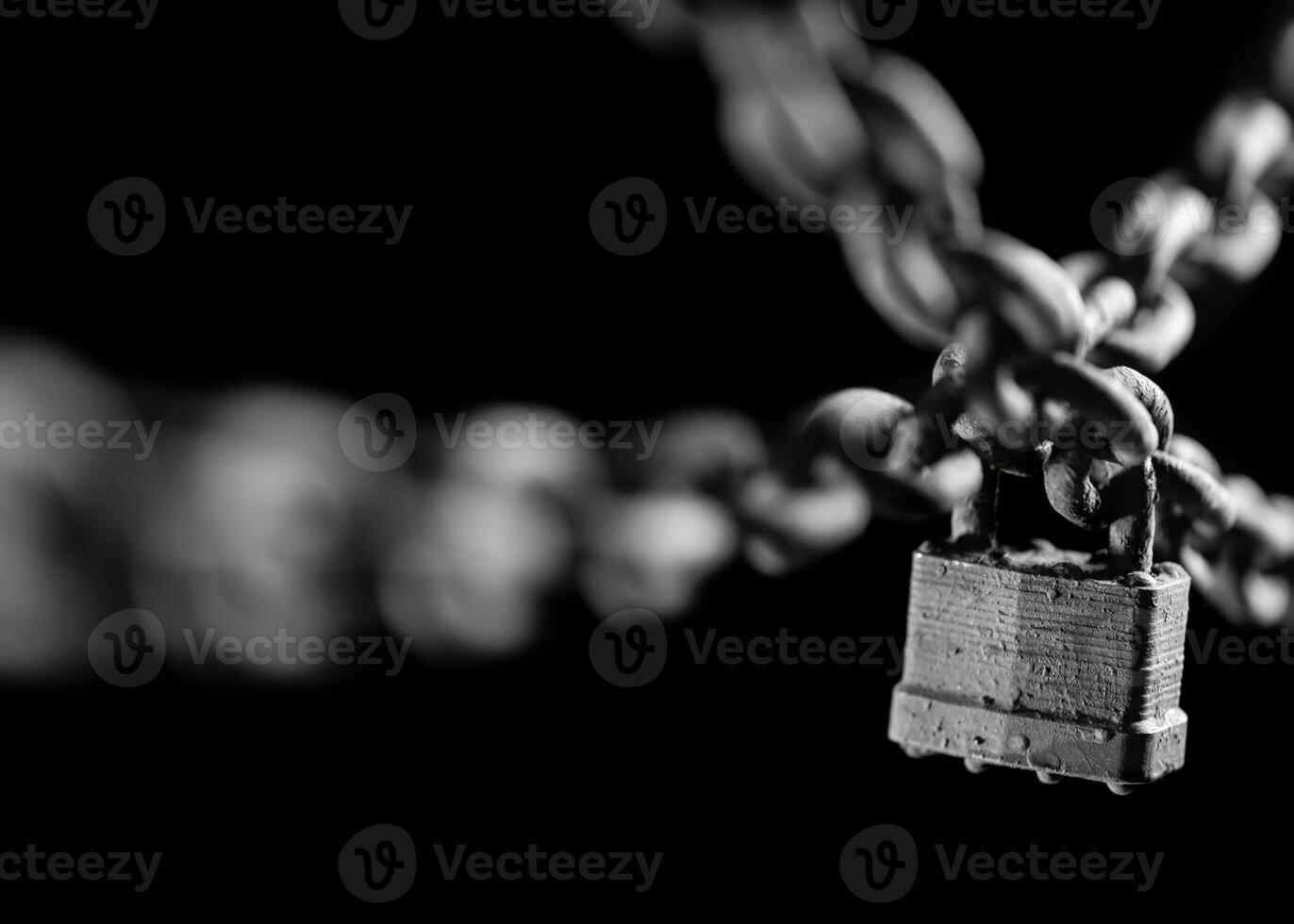 Worn rusted chain and pad lock on black background. Conceptual strength, protection, or security system. Shallow DOF. photo