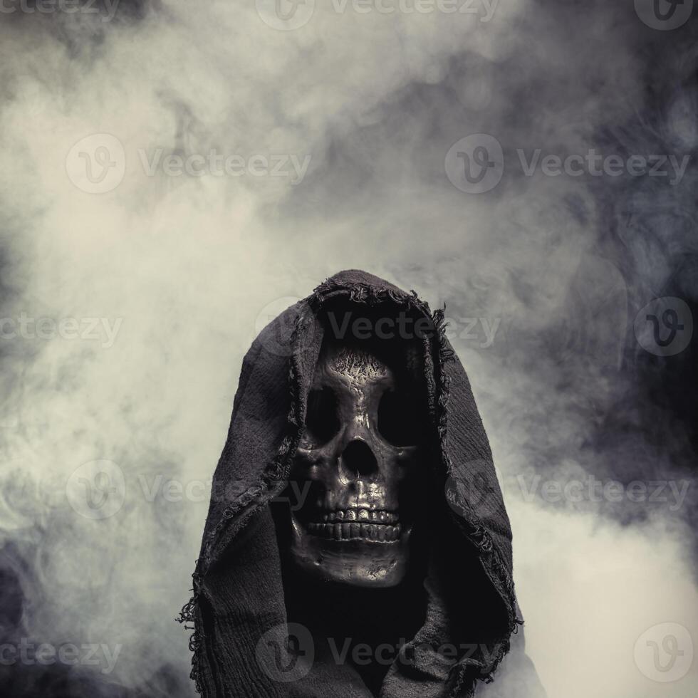 Hooded Grim Reaper figure emerging from the fog. Terrifying human skull, haunted spirt, or frightening ghost rising from dead. photo