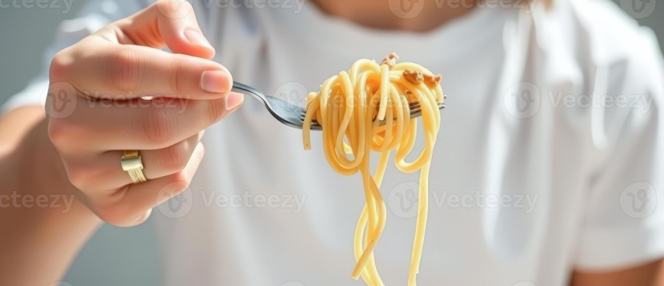 Close up of woman's hand holding a fork with spaghetti photo
