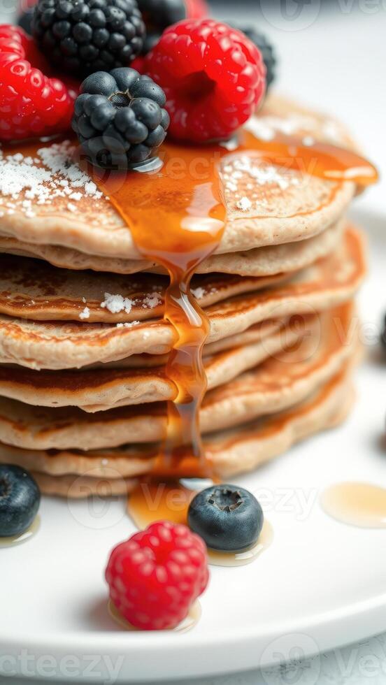 Stack of pancakes with berries and maple syrup photo