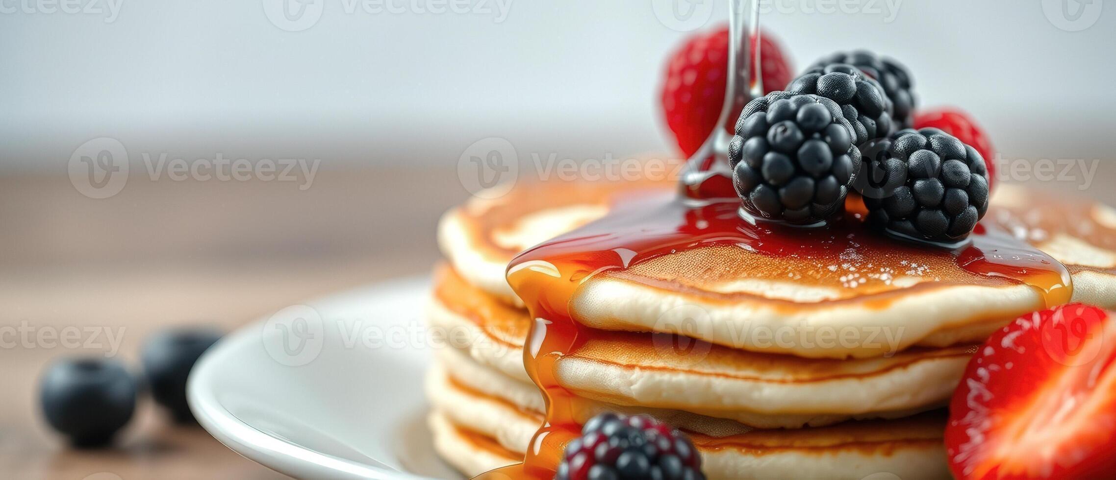 Stack of pancakes drizzled with syrup and topped with fresh fruit photo