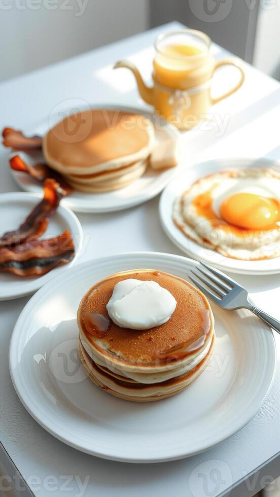 Stack of Pancakes with Butter and Syrup, Fried Egg, and Bacon on a White Table photo