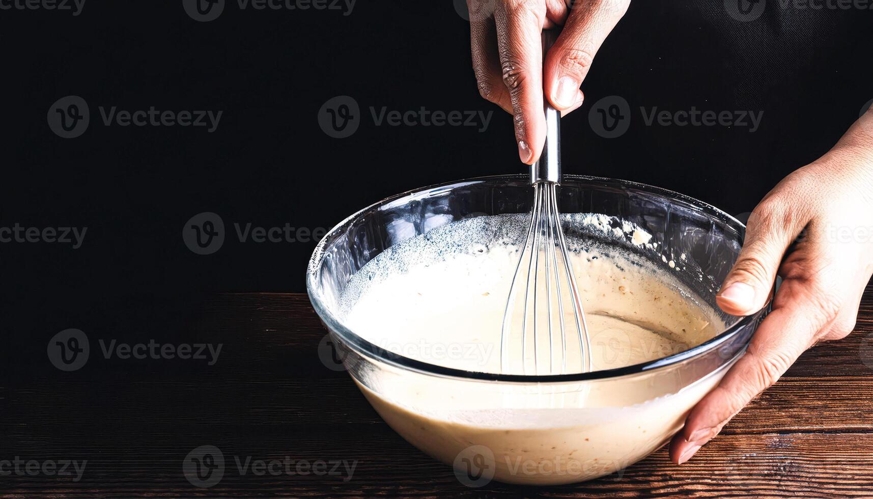 Close-up of a hand whisking batter in a glass bowl photo
