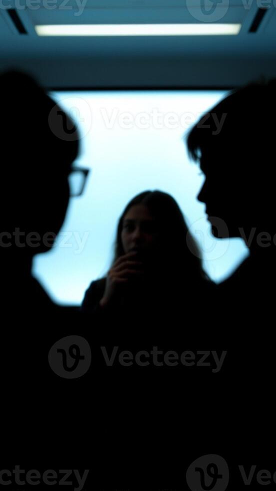 Silhouettes of three people in an elevator photo